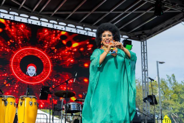 Female performer in green singing at the Three Kings Parade