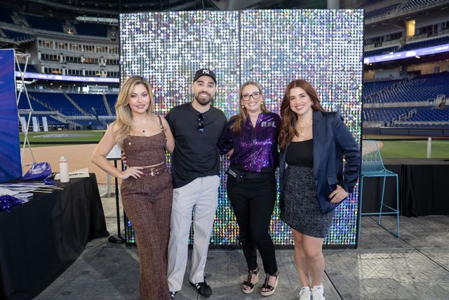 Four Give Miami Day guests posing together in front of a sequined backdrop