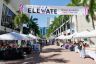 Outdoor vendor market beneath an Elevate Small Business banner in downtown Miami
